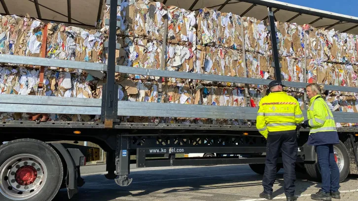 Inspectie door twee mannen van vrachtwagen met oud papier 