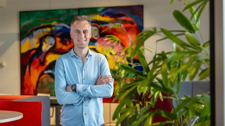 DICTU colllega Olaf Sloot staat voor een rood gevlamd schilderij