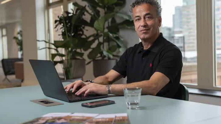 Mo Fneish: man zittend achter tafel met een laptop