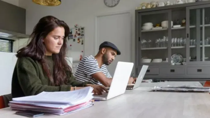 Vrouw en man werkend op laptop aan keukentafel