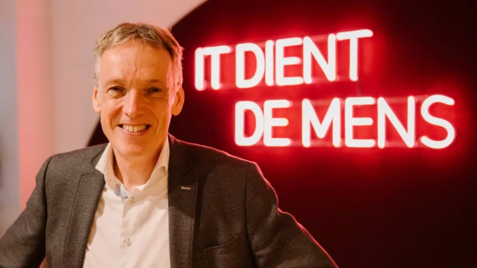 Teun van der Vorm voor een neon-tekst met de woorden IT dient de mens